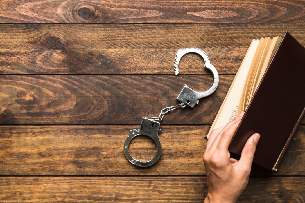 Intentional legal and ethical lapses contributed to the glut of asylum scandals. A man flipping through a book with handcuffs on the table.