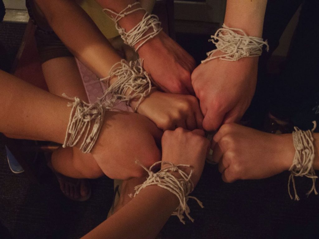 People touching their fists together while bound with rope.